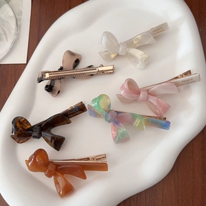 Set of 6 tortoiseshell acetate bow hair clips in pastel colors on a white ceramic tray