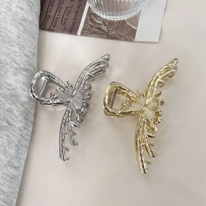 Close-up of gold and silver butterfly hair claws with opal stone inlay details