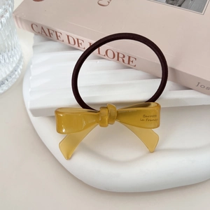 Detail of an amber acetate bow hair tie on a white tray with French cafe style decor