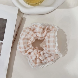 Detail of pink and white checkered scrunchie with lace trim on a lifestyle background