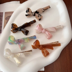 Close-up of six handmade acetate bow hair clips with France engraving on golden clips