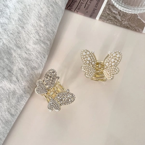 Eleganti mollette per capelli a farfalla dorate con perle e strass su sfondo chic