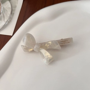 Detail of cream acetate bow hair clip with France Handmade text on ceramic tray