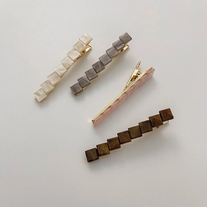 Close-up of geometric square hair clips in four colors with marble pattern and gold metal base