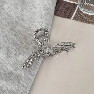 Detailed close-up of metallic butterfly hair claw clip with cat eye stones on knit fabric