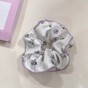 Close-up of a floral purple hair scrunchie with detailed stitching on fabric