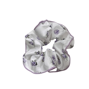 Floral fabric scrunchie with purple rose patterns and stitched edges in French style