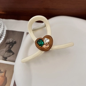 Detail view of cream heart hair claw clip with emerald and teardrop rhinestones