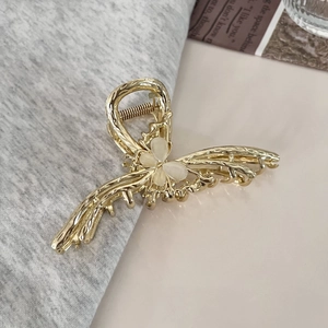 Close-up of golden metal butterfly hair claw clip with opal stones on a soft fabric