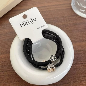 Detail of high-elastic black hair ties with heart rhinestone and flower charm on card