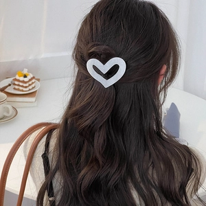 Elegant heart-shaped acetic acid hair clip shown on dark brown long wavy hair back view