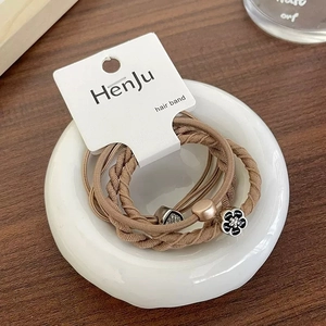 Detail of coffee-colored elastic hair bands with rhinestone heart and black flower charms