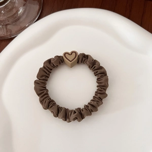 Minimalist dark brown scrunchie with heart charm on a white ceramic plate