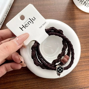Detail of dark brown braided hair tie with cross-star button and matte bead accessory
