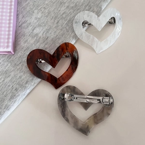 Detailed macro view of heart-shaped acetate hair clips with various marble and tortoiseshell textures