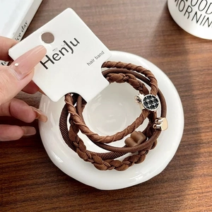 Detailed view of four brown high-elastic hair ties with cute charms on a white plate