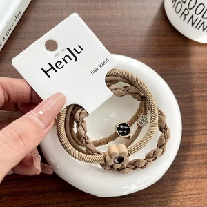 Detailed view of elastic hair bands with heart charms and floral accents in earthy tones
