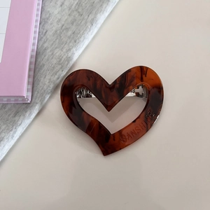 Detail of tortoise shell heart hair clip with silver spring mechanism on a table