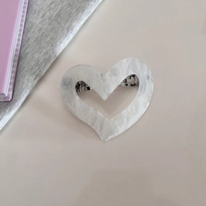 Detailed macro view of heart-shaped acetate hair clip with silver spring metal fastener