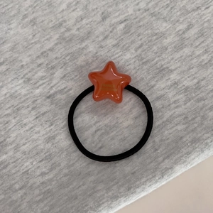 Gros plan sur l'élastique étoile en résine orange avec texte doré France Handmade et cordon noir
