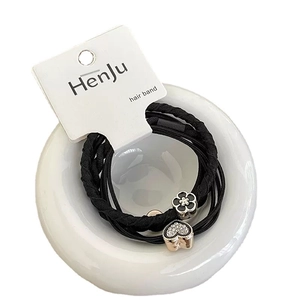 Elastic black hair ties set with heart-shaped diamond and floral charms in a ceramic bowl