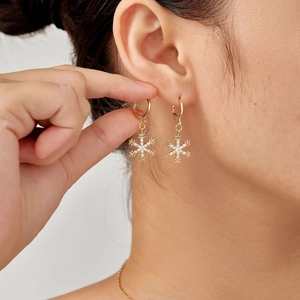 Elegante goldene Schneeflocken-Ohrringe mit Zirkonia-Steinen an einem Model