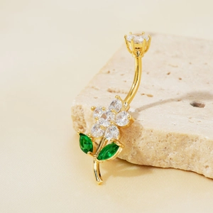 Piercing de nombril doré avec fleur en zircone et feuilles vertes sur pierre naturelle