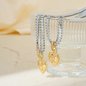 Goldene Herzanhänger-Halskette mit Zirkonia-Buchstabe und Kristall-Tenniskette am Glas