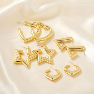 Golden geometric earrings set including heart star and triangle studs on satin fabric
