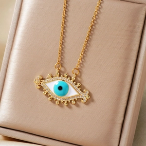 Elegant gold evil eye pendant necklace with blue zircon inlay on champagne satin background