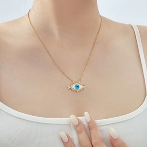 Detail of gold evil eye pendant necklace with blue center and sparkling zircons on model