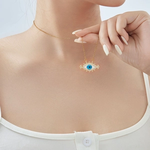 Gold evil eye necklace with blue zircon and crystal accents on a model neckline