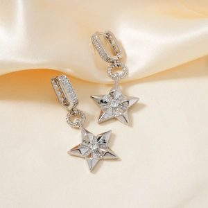 Detalle macro de pendientes de estrella plateados con circonitas blancas micro-pavé