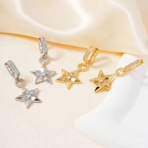 Elegantes pendientes de estrella en oro y plata sobre fondo de seda champán