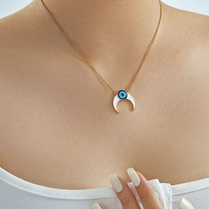 Dettaglio ravvicinato di una collana d'oro con mezzaluna bianca e ciondolo malocchio