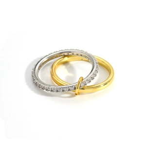 Dettaglio degli anelli intrecciati in oro e argento con castone di pietre zirconi