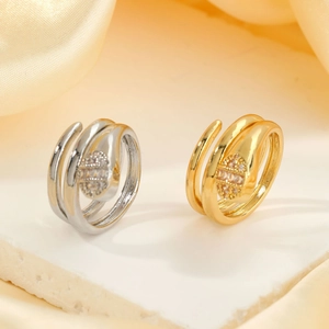 Elegant gold and silver snake coil rings with sparkling cubic zirconia on stone pedestal