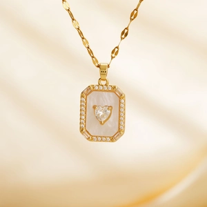 Elegante goldene Halskette mit Herz-Zirkonia und weißer Muschel auf Seidenhintergrund