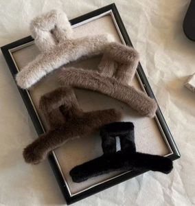 Detail of four fuzzy faux fur claw clips in beige brown and black for thick hair