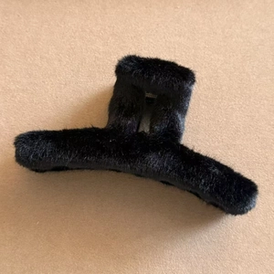 Detailed view of the soft black faux fur hair claw clip on a neutral felt background