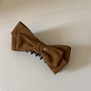 Detail of the caramel velvet bow hair claw clip with golden Love engraving tag