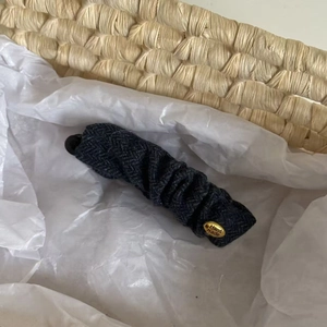 Vintage dark gray herringbone banana hair clip with handmade gold emblem in a woven basket