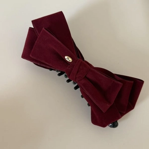 Macro shot of large burgundy velvet bow hair clip featuring a gold Love metal clasp detail