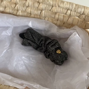 Detail of herringbone pattern fabric banana hair clip with golden hand made metal tag