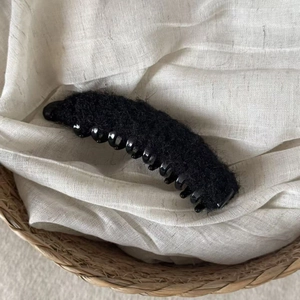 Plush black faux fur banana hair clip on natural woven basket background