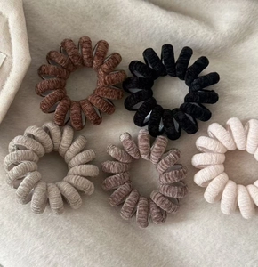 Détail de cinq chouchous spirales en velours aux couleurs d'automne sur fausse fourrure douce