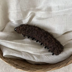 Caramel brown plush banana hair clip in soft faux shearling on a textured linen background