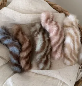 Détail de cinq barrettes à cheveux en peluche aux tons automnaux sur fond tissé rustique
