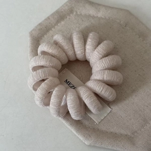 Détail de l'élastique spirale en velours beige sur support cartonné hexagonal texturé