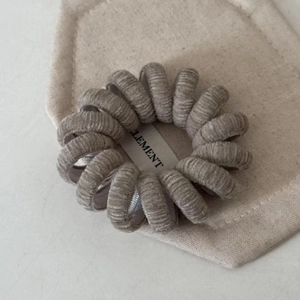 Détail macro d'un élastique spirale en velours gris avec une étiquette tissée blanche